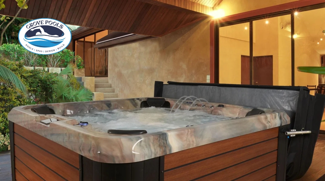 Luxury Strong Spas hot tub filled with bubbling water on a covered patio, surrounded by tropical plants, installed by Grove Pools.